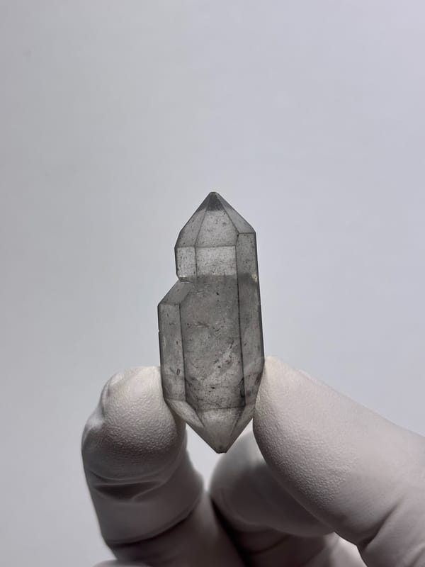 Sketch-pattern double-terminated quartz with flowered tips from Yunnan, China, held in gloved hand