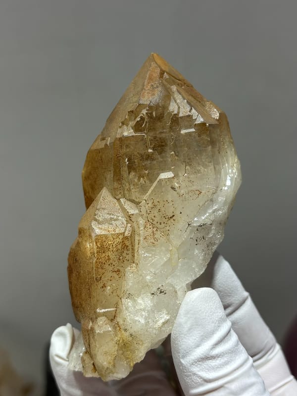 Golden quartz point with sculpted form from Xuebaoding, Sichuan, China, held in gloved hand