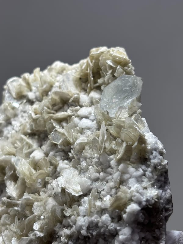 Pale mica plate with small aquamarine crystal from Xuebaoding, Sichuan, China, close-up of the crystal faces
