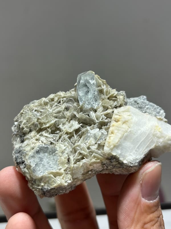 Mica plate with aquamarine on both faces and feldspar from Xuebaoding, Sichuan, China, held in hand