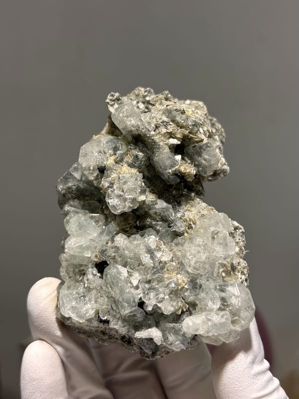 Cluster of pale green aquamarine crystals on dark mica from Xuebaoding, Sichuan, China, close-up of the crystal faces