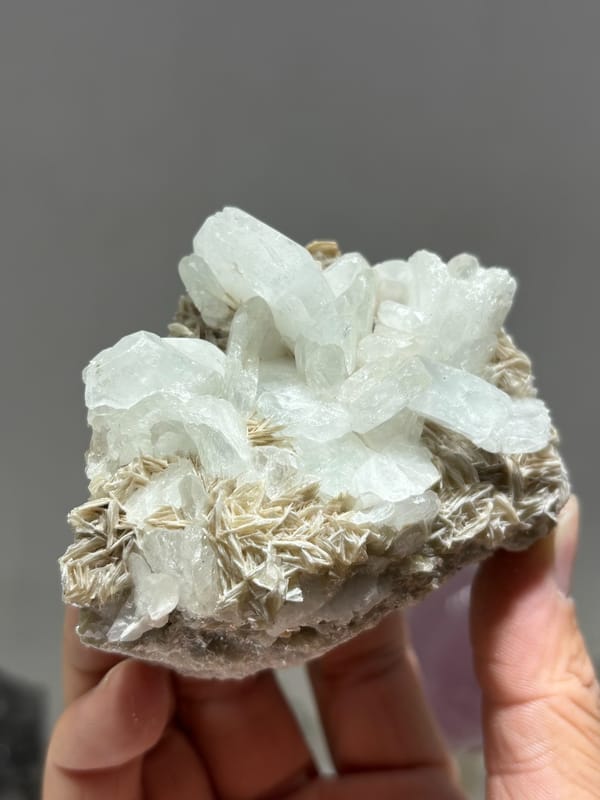 Pale aquamarine cluster on tan mica from Xuebaoding, Sichuan, China, close-up of the crystal faces