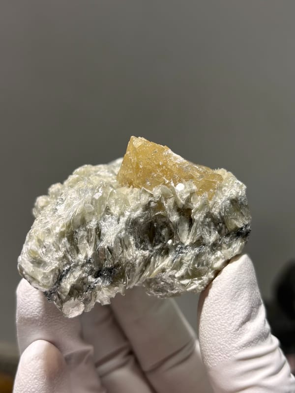 Honey scheelite on silvery mica plate from Xuebaoding, Sichuan, China, close-up of the crystal faces