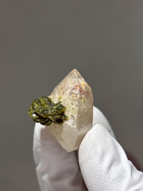 Double-terminated garden quartz with epidote cluster from Sichuan, China, held in gloved hand