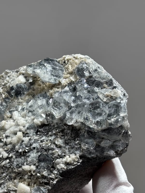 Grey plate with aquamarine, mica and feldspar from Xuebaoding, Sichuan, China, close-up of the crystal faces