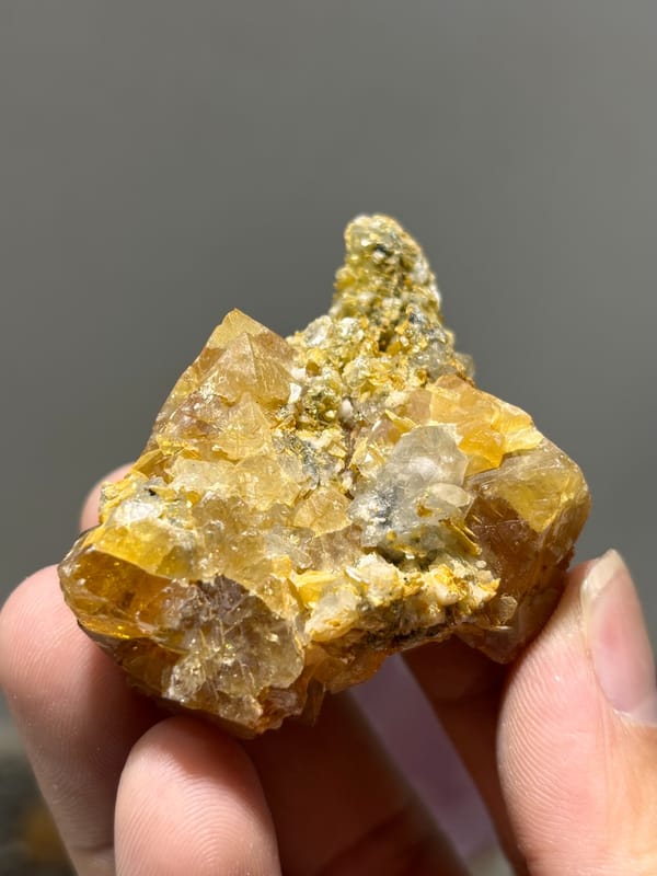 Orange scheelite with aquamarine and mica from Xuebaoding, Sichuan, China, held in hand