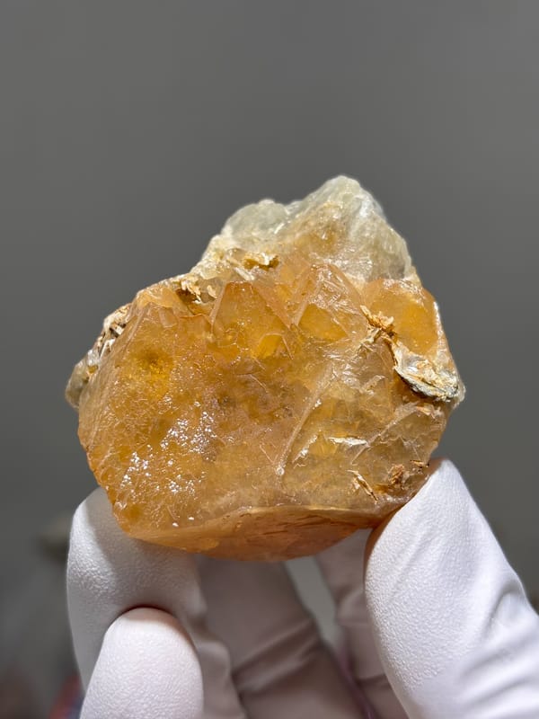 Large honey-orange scheelite on tan mica from Xuebaoding, Sichuan, China, close-up of the crystal faces