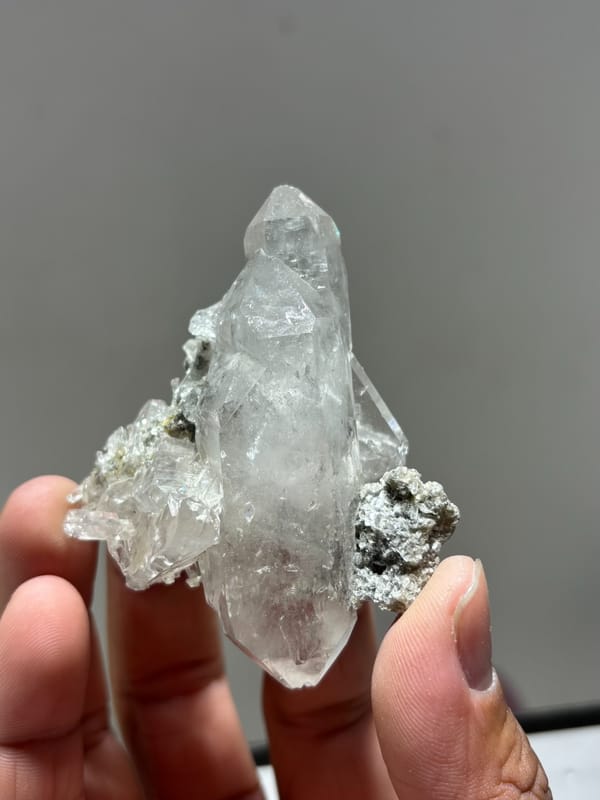 Clear quartz cluster with mica and dark flecks from Xuebaoding, Sichuan, China, close-up of the crystal faces