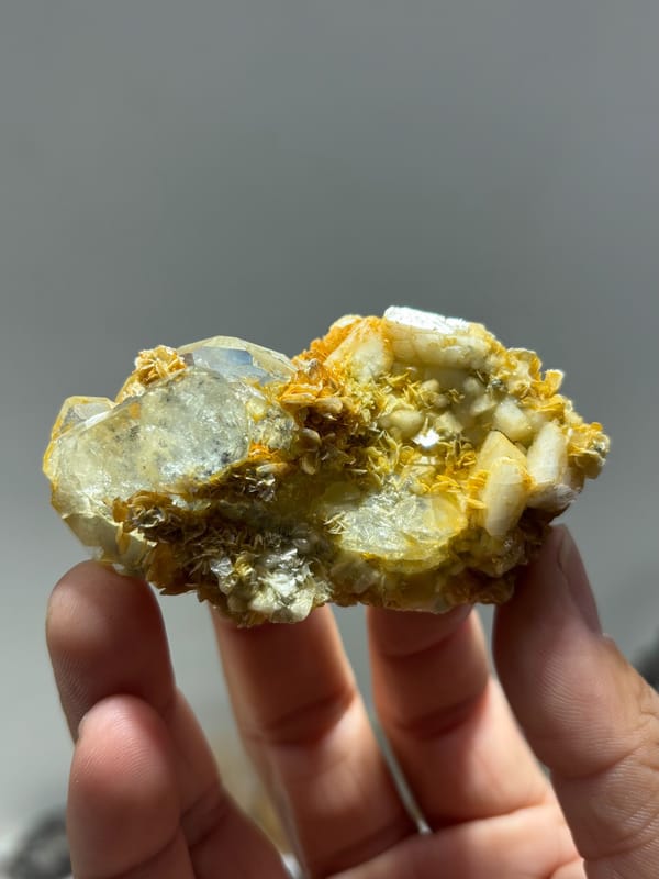 Two-sided aquamarine plate with golden mica and feldspar from Xuebaoding, Sichuan, China, held in hand