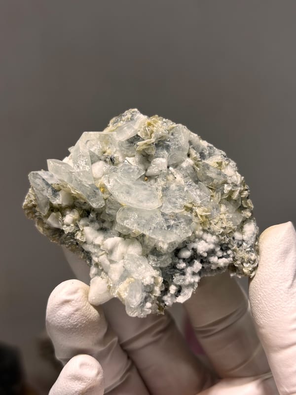 Pale aquamarine cluster over white feldspar and mica from Xuebaoding, Sichuan, China, close-up of the crystal faces