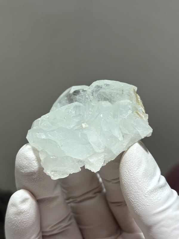 Pale aquamarine crystal group with floater base from Xuebaoding, Sichuan, China, held in gloved hand