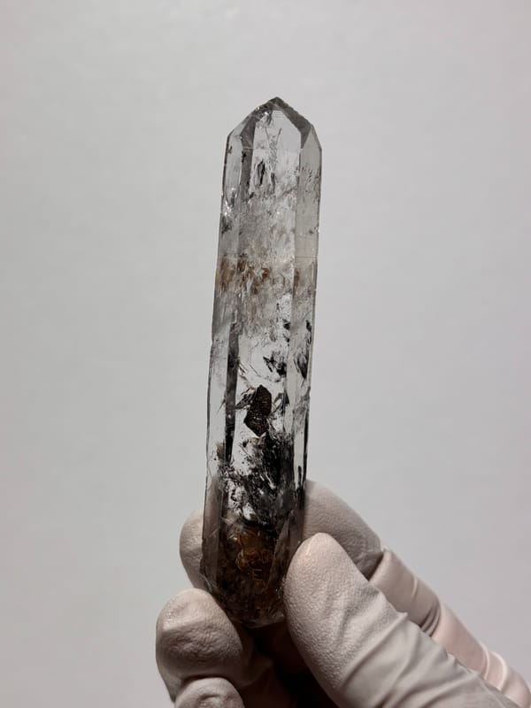 Black-included quartz wand from Jinkouhe, Sichuan, China, held in gloved hand