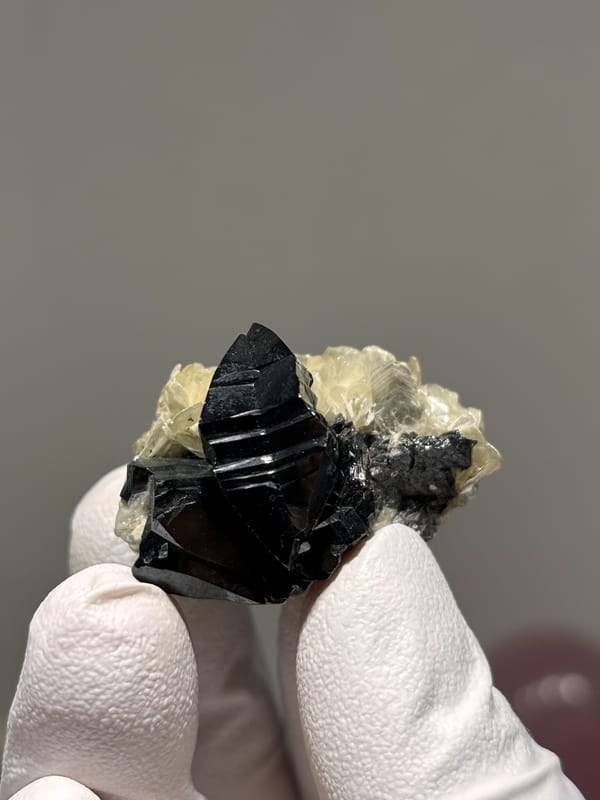 Black cassiterite crystal on pale mica rosettes from Xuebaoding, Sichuan, China, second angle