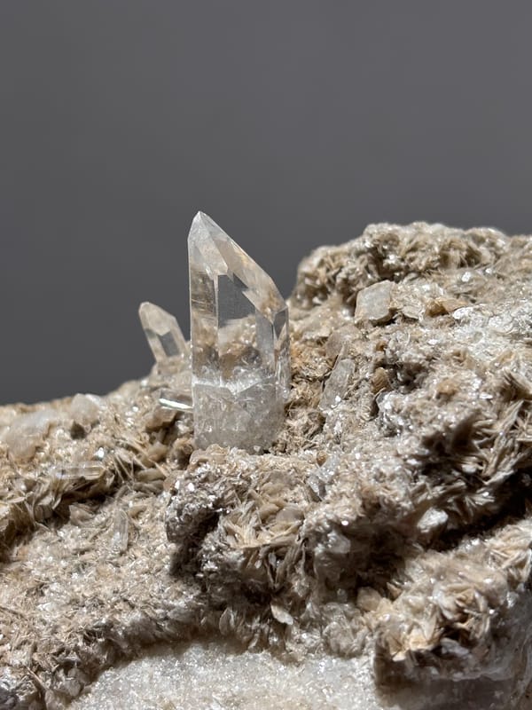 Grey matrix plate with small quartz prism and mica from Xuebaoding, Sichuan, China, second angle
