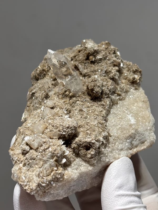 Grey matrix plate with small quartz prism and mica from Xuebaoding, Sichuan, China, close-up of the crystal faces