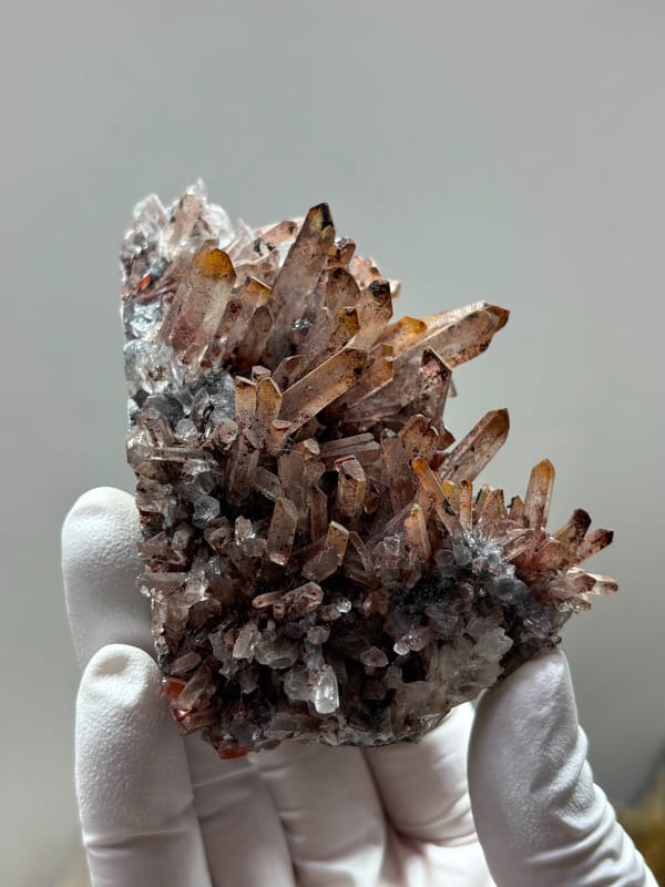 Red-skinned quartz cluster from Guangdong, China, held in gloved hand