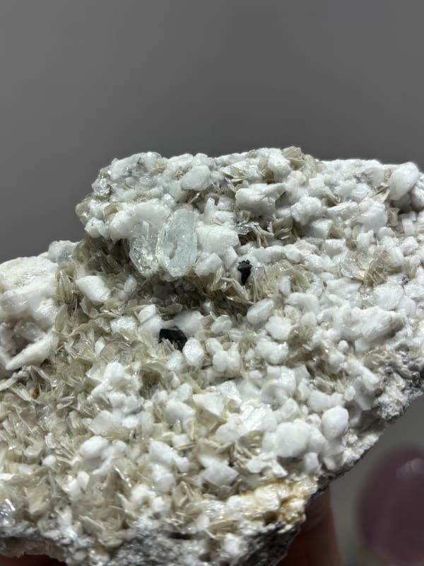 Plate of mica and feldspar with aquamarine and cassiterite from Xuebaoding, Sichuan, China, close-up of the crystal faces