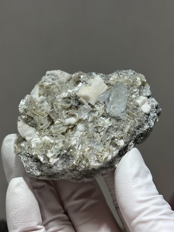 Pale aquamarine in grey mica with white feldspar from Xuebaoding, Sichuan, China, close-up of the crystal faces