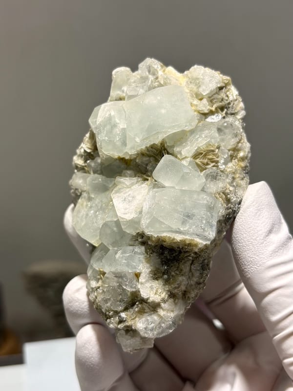 Pale aquamarine prisms lying on grey mica from Xuebaoding, Sichuan, China, close-up of the crystal faces