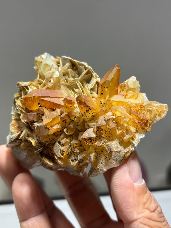 Golden-stained quartz on mica with aquamarine from Xuebaoding, Sichuan, China, held in hand