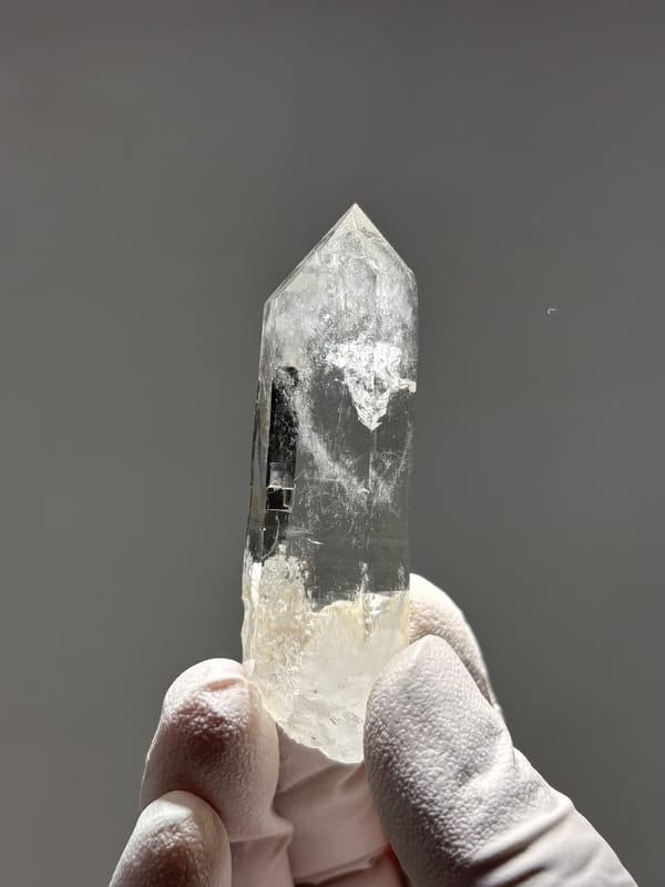 Bright clear quartz point with chlorite base from Xuebaoding, Sichuan, China, close-up of the crystal faces
