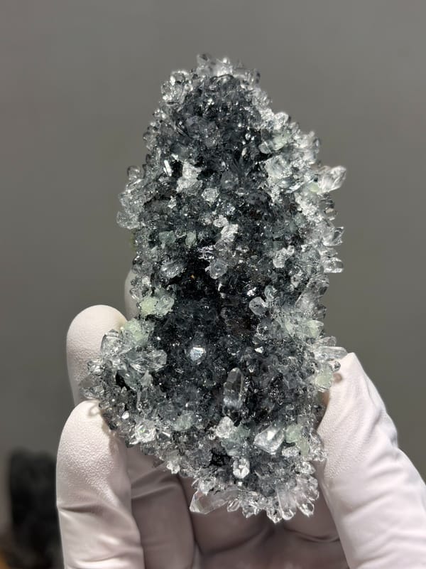 Plate of quartz on prehnite from Yunnan, China, held in gloved hand