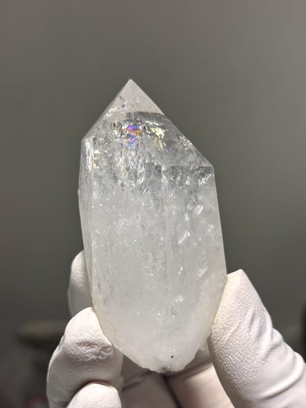 Icy clear quartz point with rainbow flash from Jinkouhe, Sichuan, China, close-up of the crystal faces