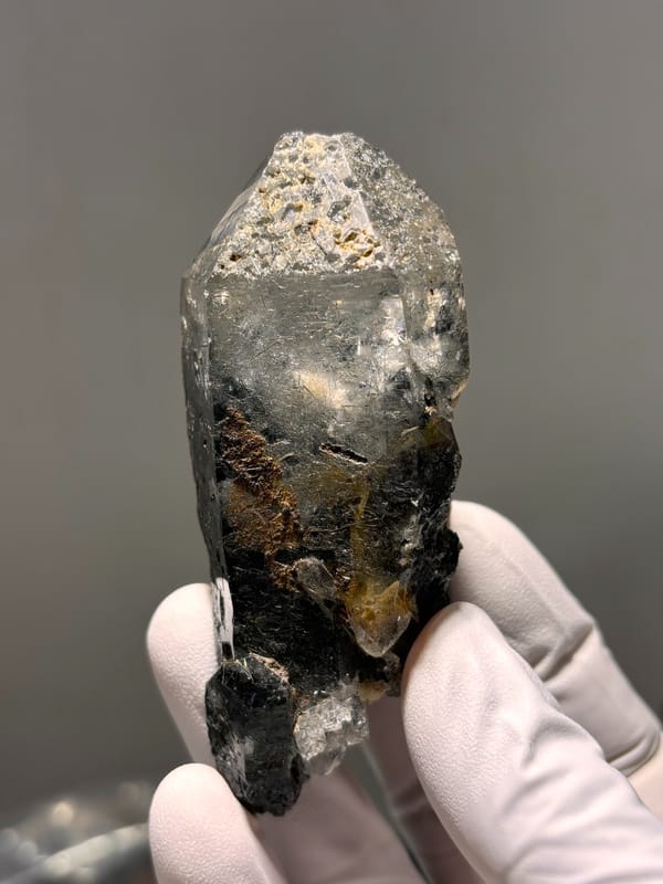 Smoky quartz point with black rutile on dark base from Xuebaoding, Sichuan, China, close-up of the crystal faces