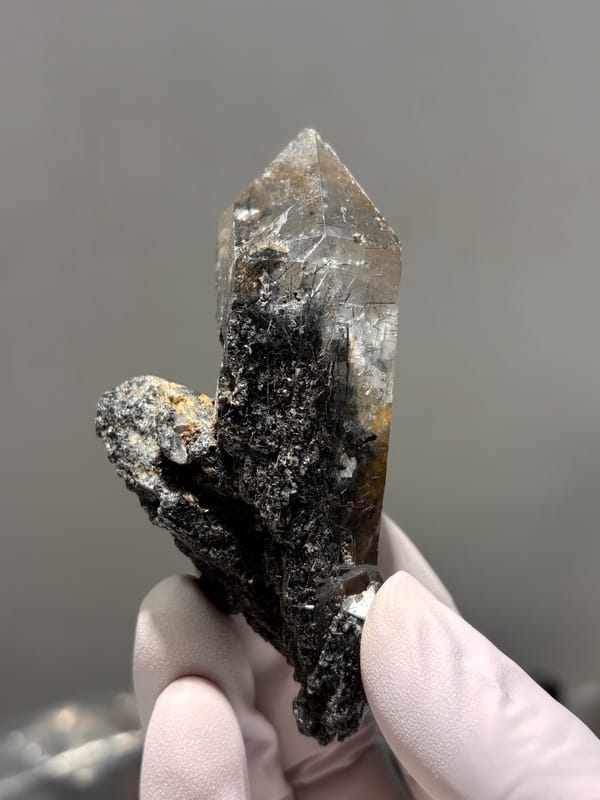 Smoky quartz point with black rutile on dark base from Xuebaoding, Sichuan, China, top view