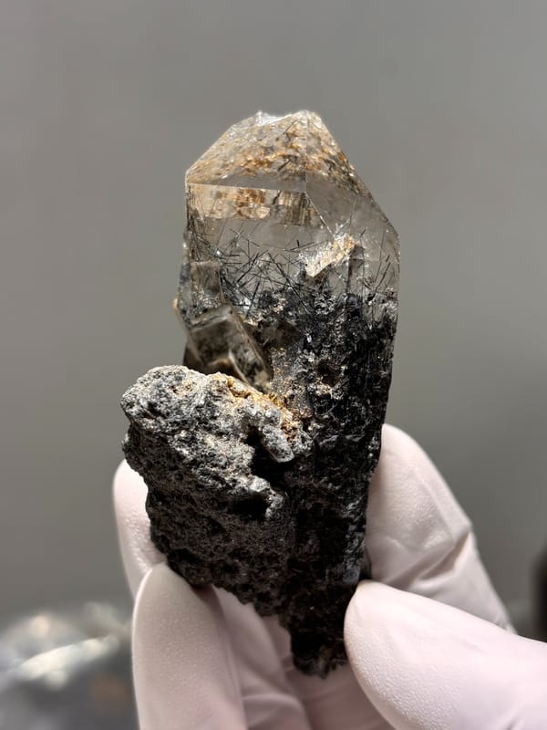 Smoky quartz point with black rutile on dark base from Xuebaoding, Sichuan, China, detail of the matrix contact