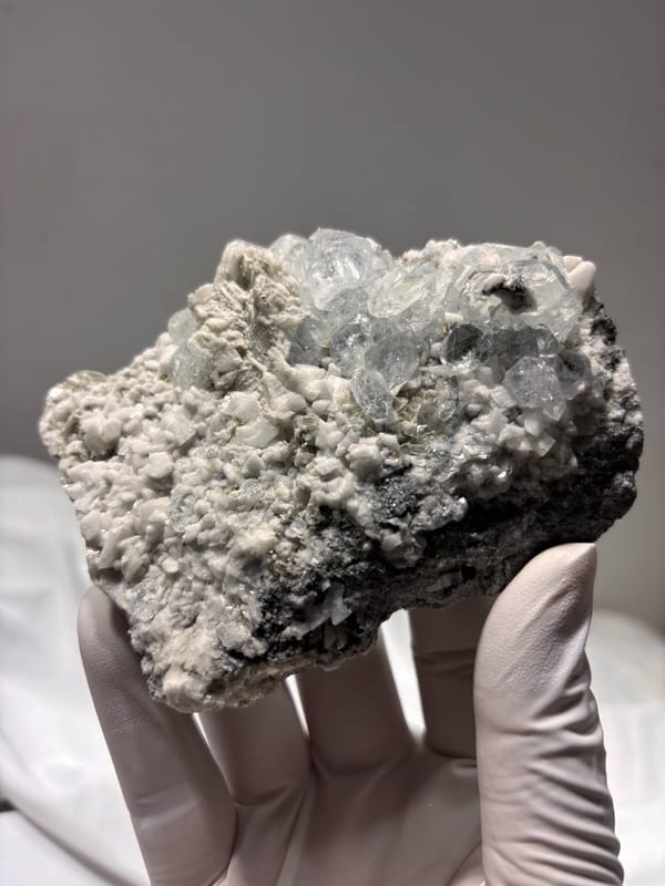 Aquamarine and mica plate from Xuebaoding, Sichuan, China, held in gloved hand
