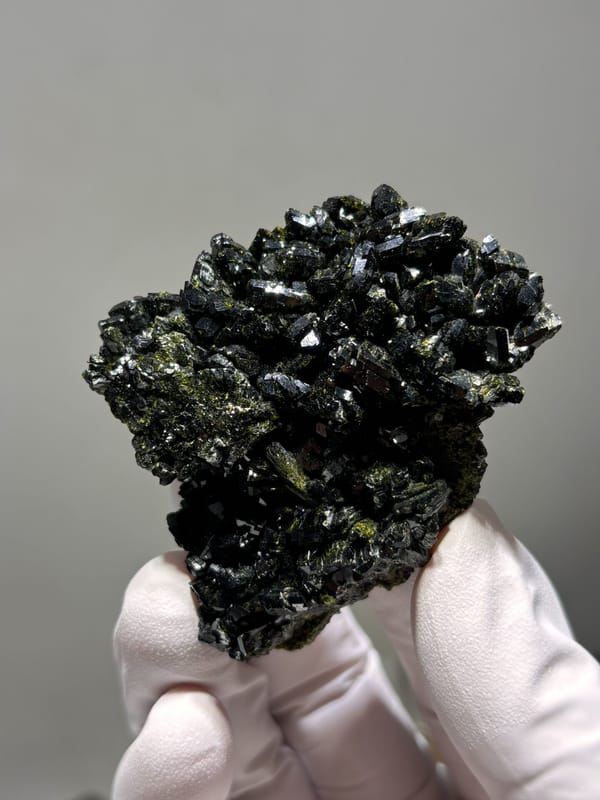 Dark green epidote cluster from Turkey, held in gloved hand