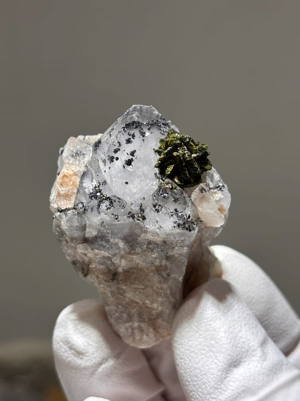 Garden quartz with ball of green epidote from Sichuan, China, held in gloved hand