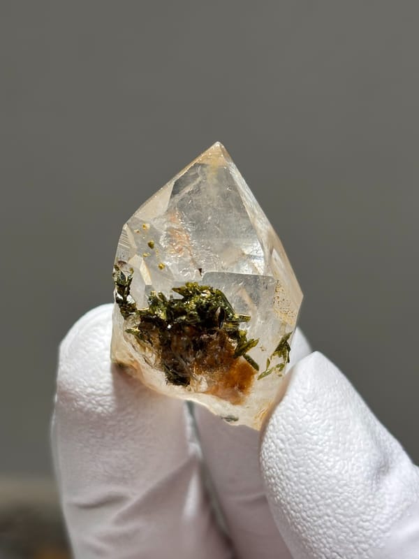 Garden quartz with green and orange inclusions from Jinkouhe, Sichuan, China, held in gloved hand
