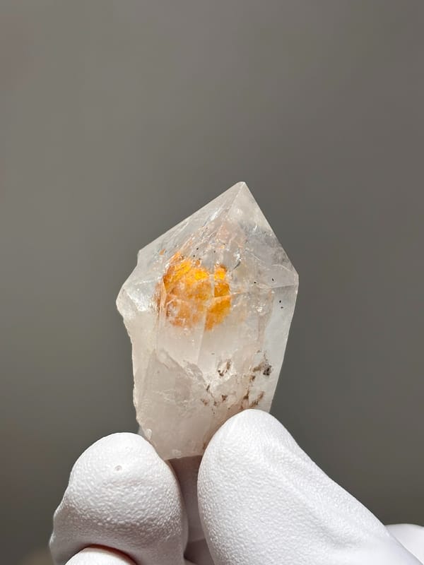 Garden quartz with bright orange inclusion from Sichuan, China, held in gloved hand
