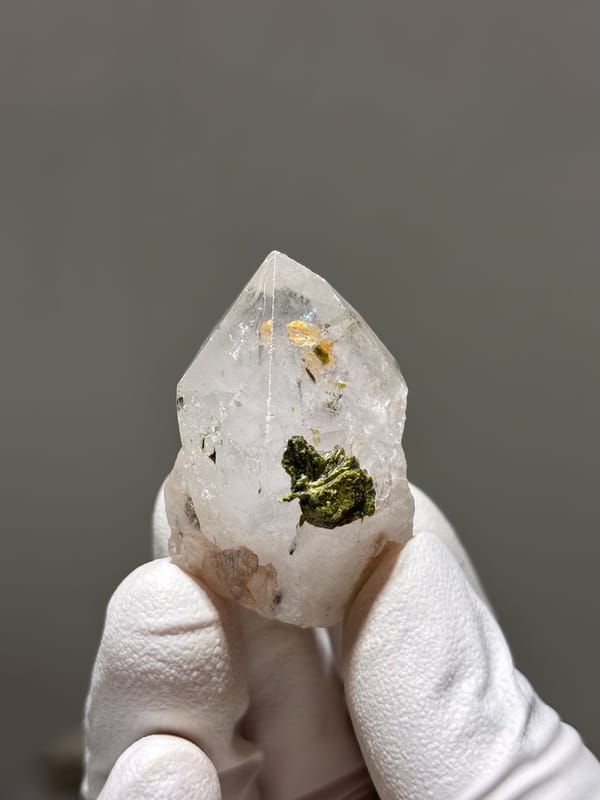 Garden quartz point with green epidote inclusion from Sichuan, China, held in gloved hand