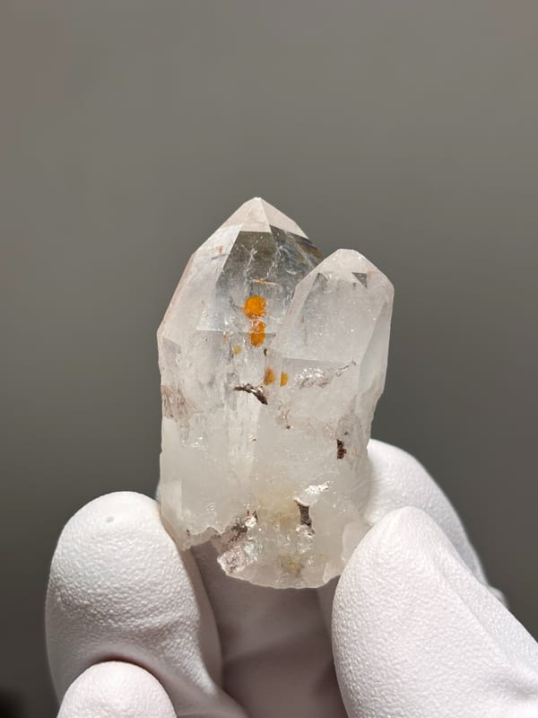 Garden quartz with orange specks inside from Sichuan, China, held in gloved hand