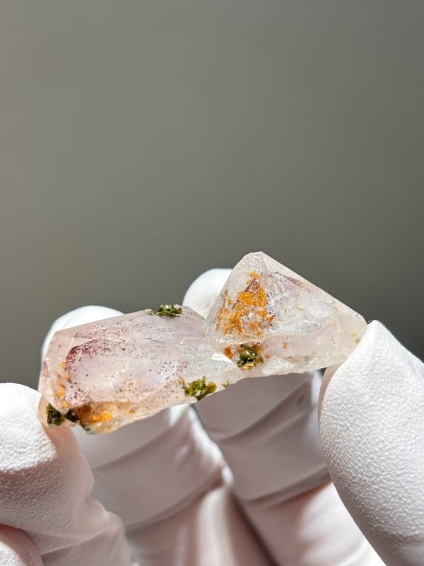 Flat garden quartz with green and orange inclusions from Sichuan, China, held in gloved hand
