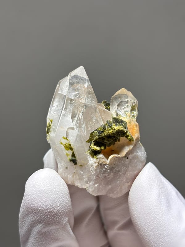 Garden quartz cluster with green and orange inclusions from Sichuan, China, held in gloved hand