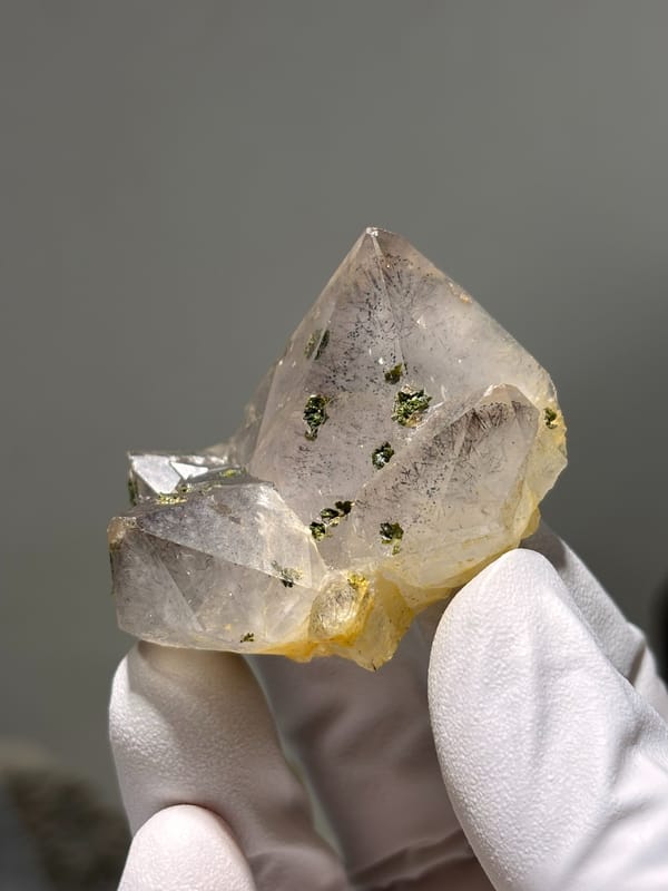 Garden quartz cluster with green epidote specks from Sichuan, China, held in gloved hand
