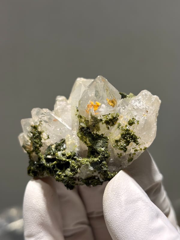 Garden quartz cluster with epidote and orange inclusions from Sichuan, China, front view in daylight, held in hand
