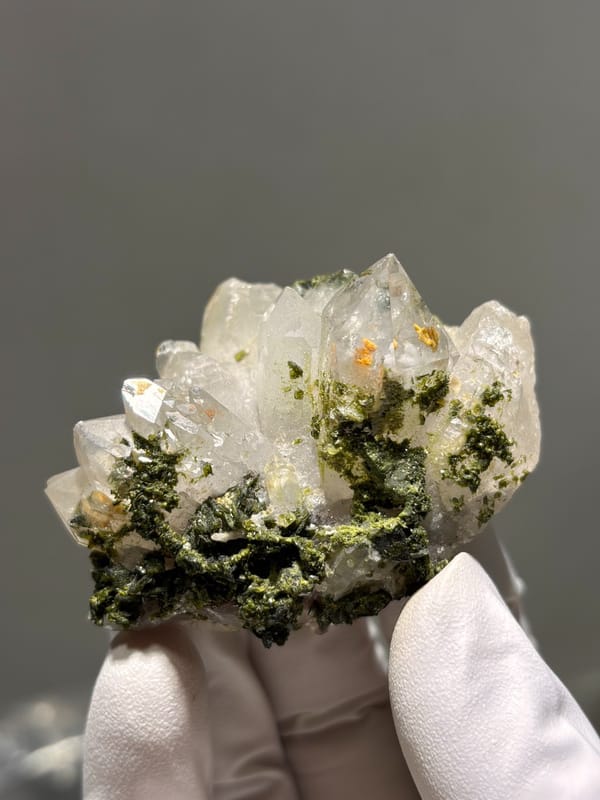 Garden quartz cluster with epidote and orange inclusions from Sichuan, China, close-up of the crystal faces