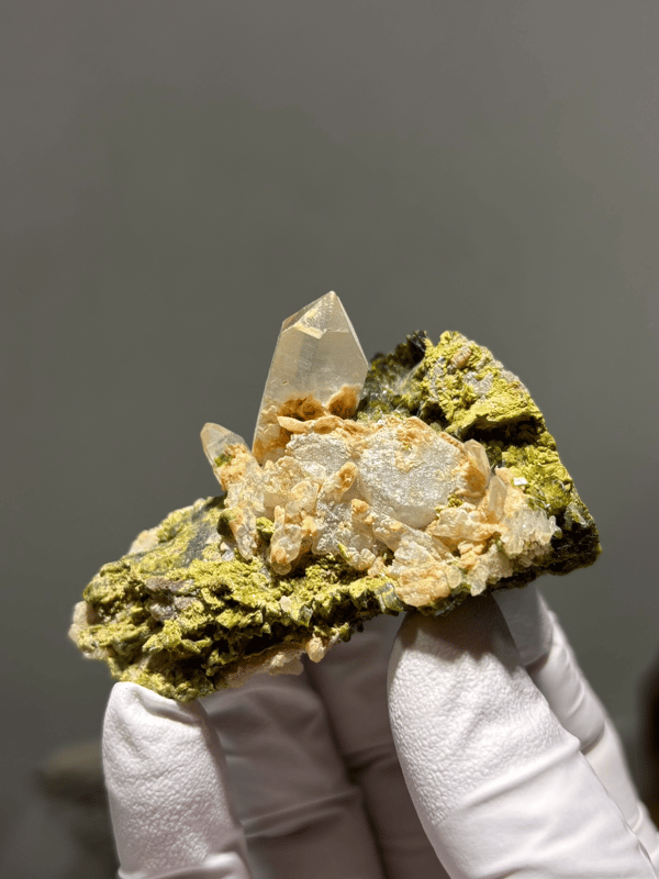 Garden quartz plate with clear points on green epidote from Sichuan, China, held in gloved hand
