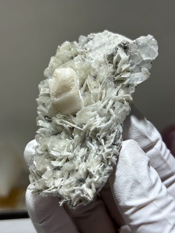 Pale mica plate with feldspar and hidden aquamarine from Xuebaoding, Sichuan, China, close-up of the crystal faces