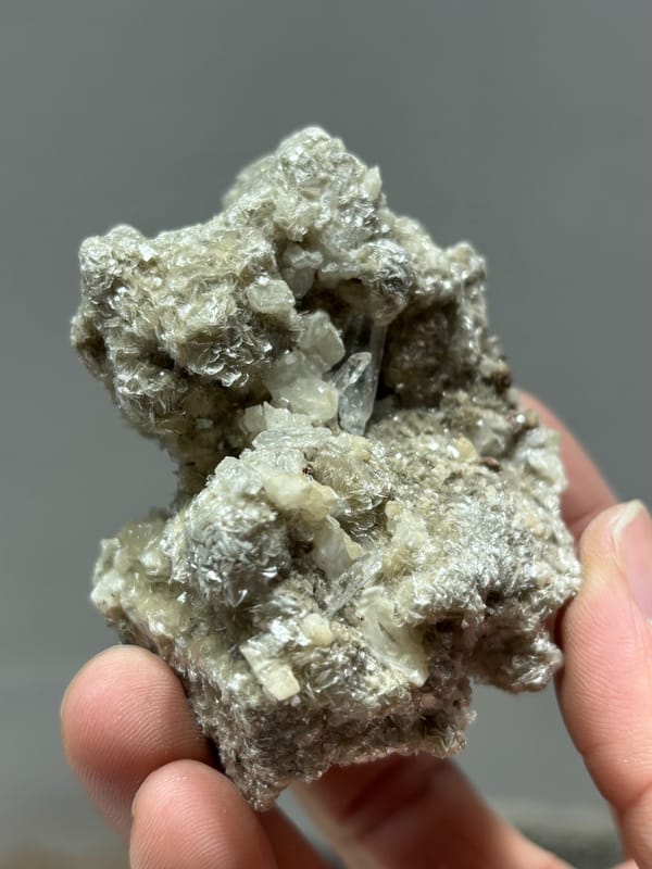 Silvery mica block with small quartz prism and white calcite from Xuebaoding, Sichuan, China, close-up of the crystal faces