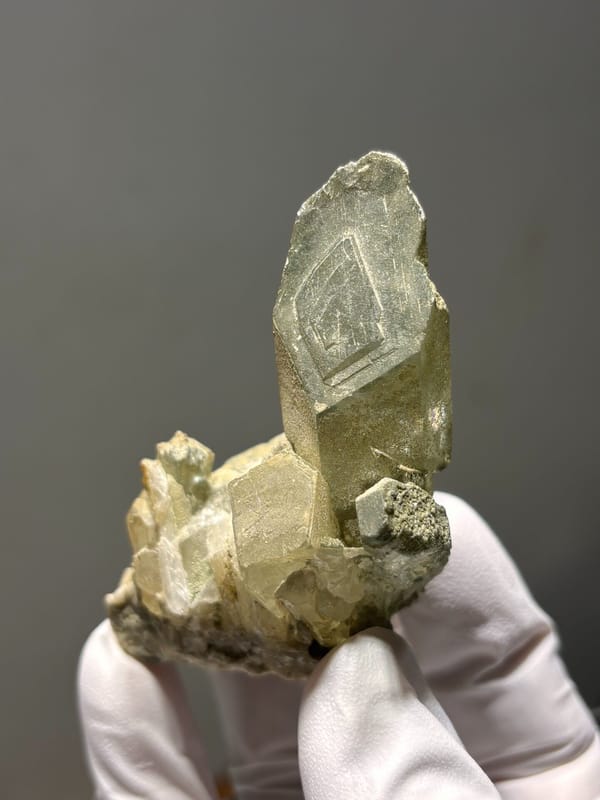 Green phantom quartz cluster from Sichuan, China, held in gloved hand