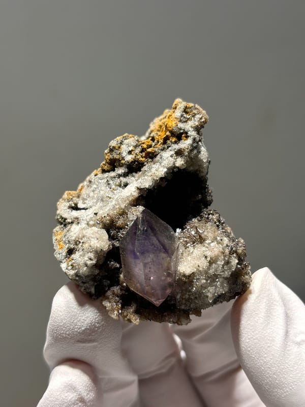 Purple amethyst point on druse matrix from Zimbabwe, close-up of the crystal faces