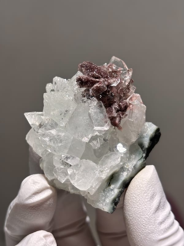 Clear apophyllite crystals with pink-brown cluster from India, close-up of the crystal faces