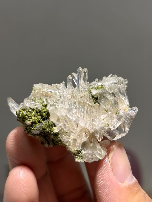 Clear quartz needles with dark green epidote from Sichuan, China, held in hand