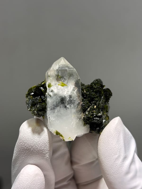 Clear quartz point on dark green epidote from Sichuan, China, close-up of the crystal faces